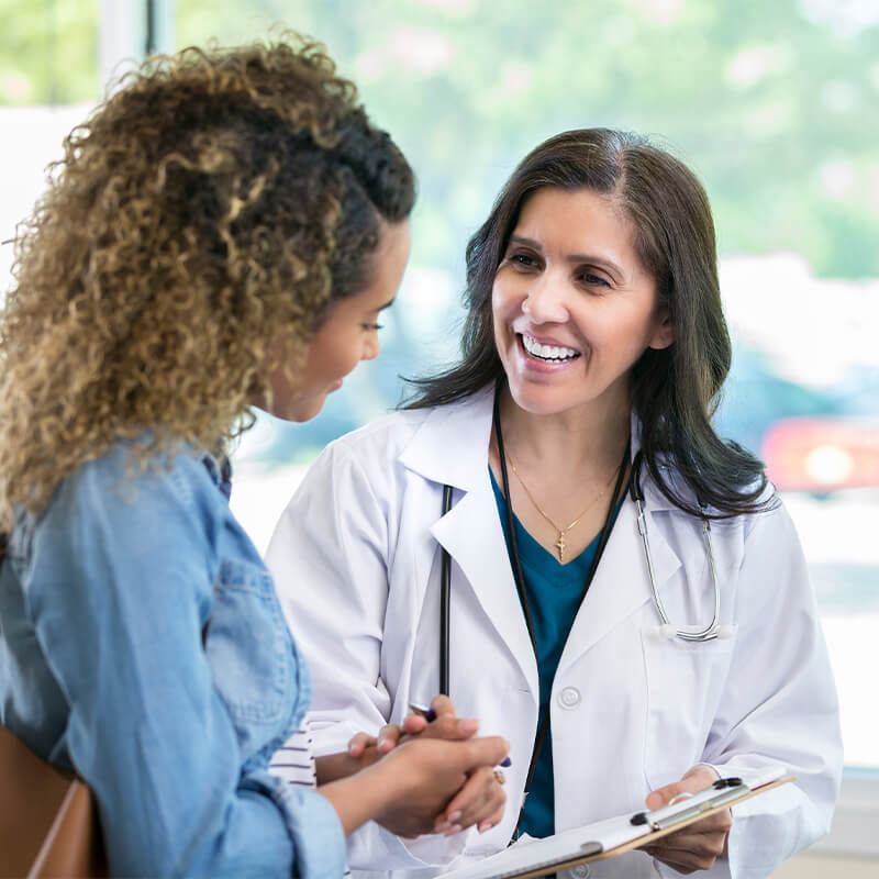 Dr. Laina Feinstein & Dr. Max Feinstein are internal medicine physicians in Southfield, Michigan. In this representative image, a medical professional smiles as she helps a patient complete forms.