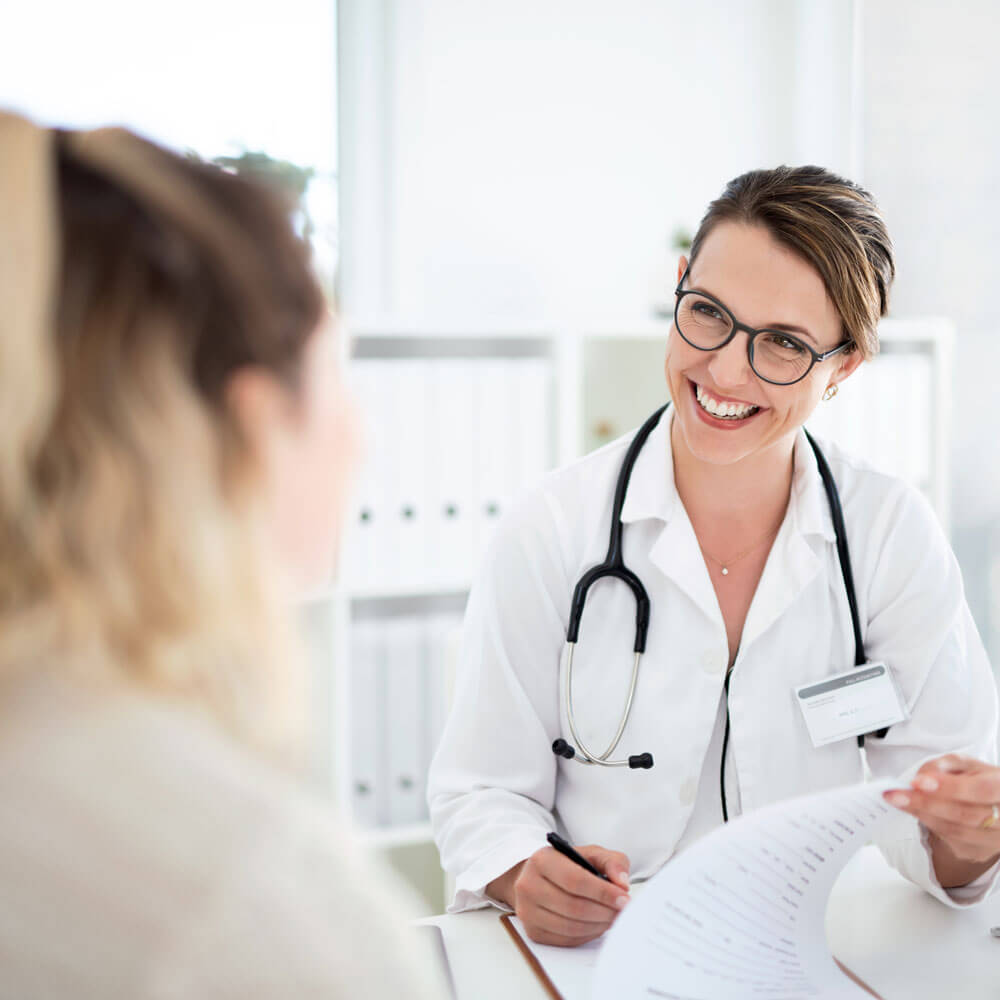Dr. Laina Feinstein, M.D., & Dr. Max Feinstein, D.O., provide internal medicine and osteopathic treatments in their Southfield, MI practice. In this representative image, a doctor smiles as she speaks with a patient in an office.
